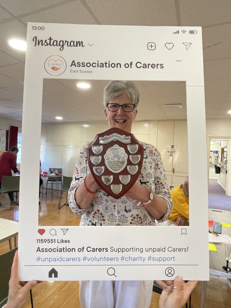 Award winner smiling holding award shield behind a cardboard Instgram frame