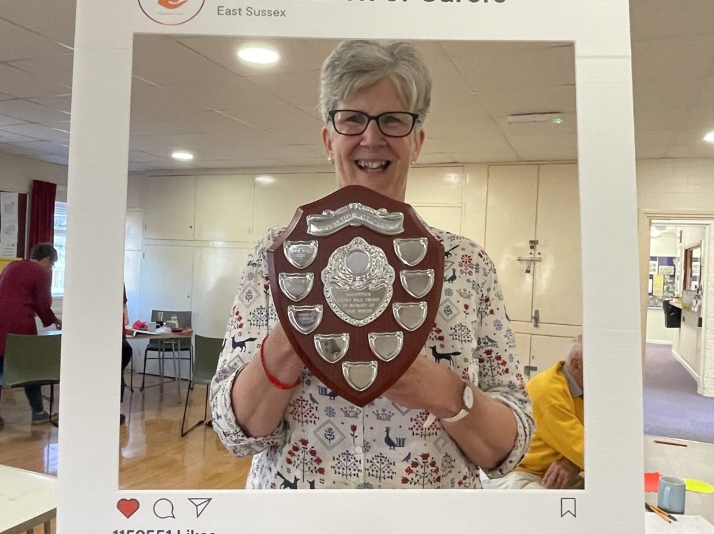 Award winner smiling holding award shield behind a cardboard Instgram frame